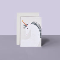Grußkarte mit weißem Einhorn, goldenem Horn, schwarzer Mähne vor lila Hintergrund, beige Umschlag
