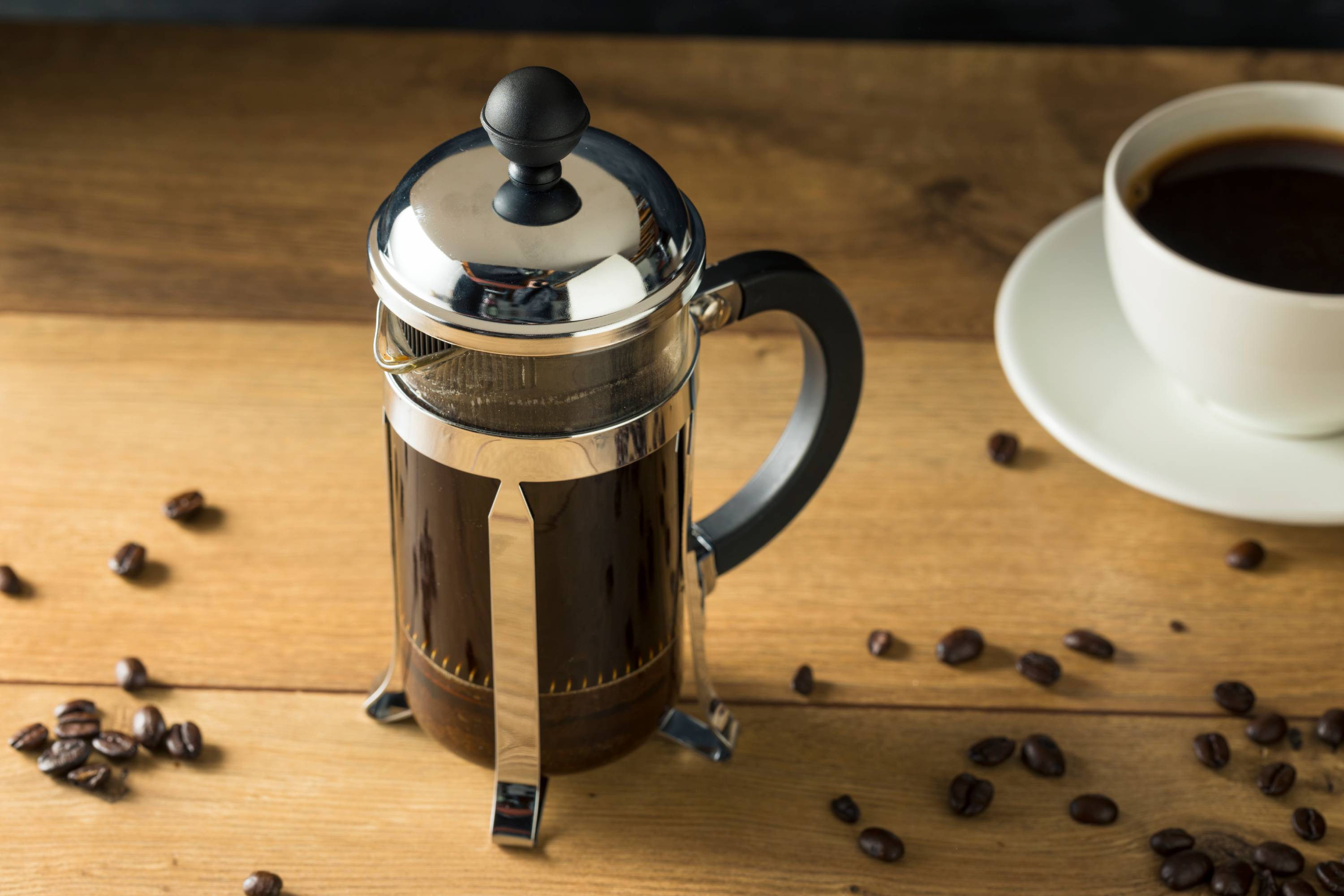 French Press zur Kaffeezubereitung auf Holztisch mit Kaffeetasse