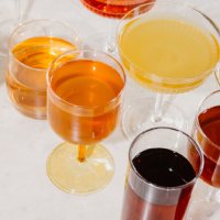 Gläser mit hellgelben, bernsteinfarbenen und dunklen Getränken, P&T Tee- und Cocktailauswahl