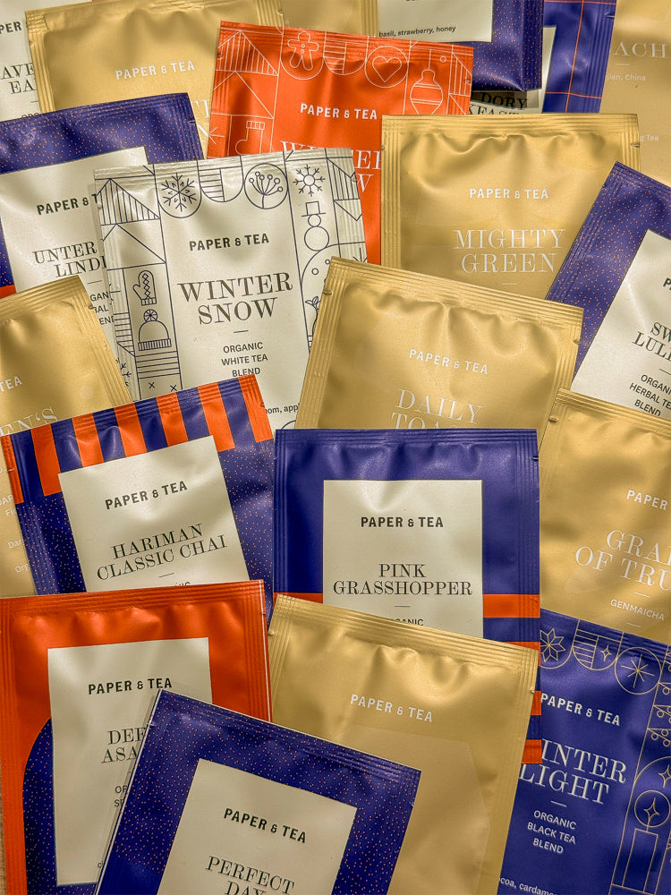Farbenfrohe PAPER & TEA Teebeutel in Gold, Orange, Blau und Creme, mit Sortennamen wie WINTER SNOW.