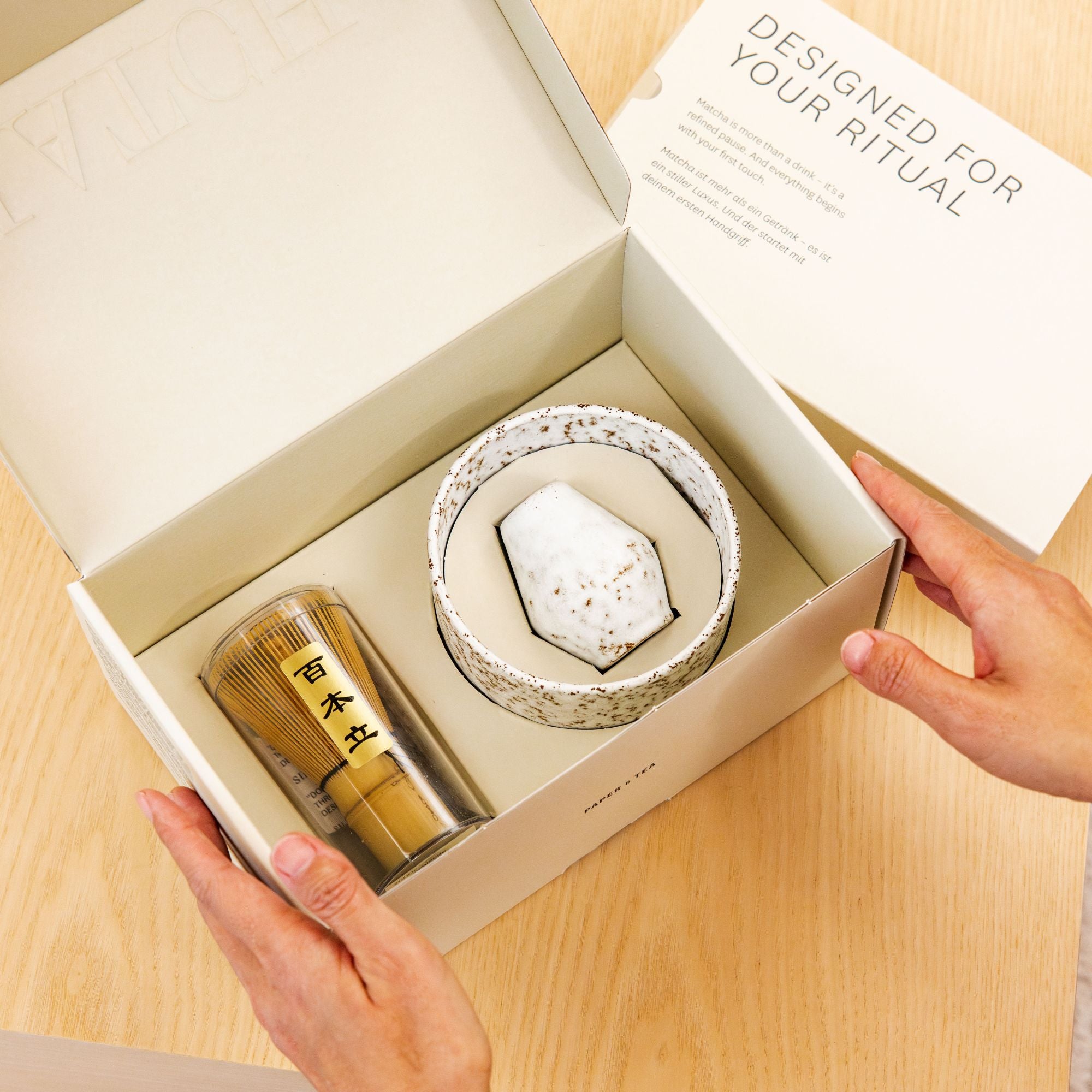Elegante Geschenkbox von Paper & Tea mit Matcha-Set aus Bambusbesen und gesprenkelter Keramikschale.