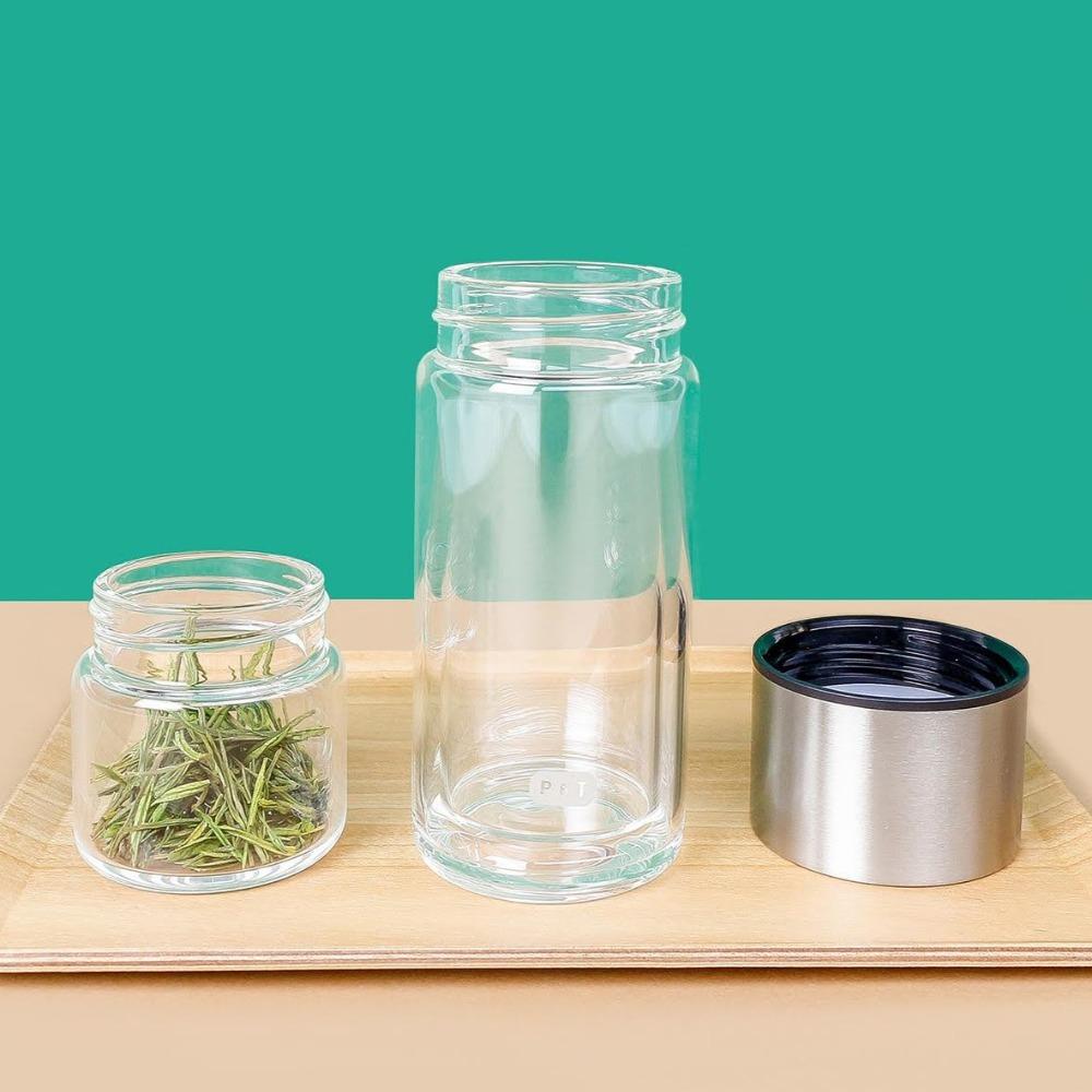 Gläser mit getrockneten Kräutern und P&T-Logo auf Holztablett vor grünem Hintergrund, minimalistisch arrangiert.