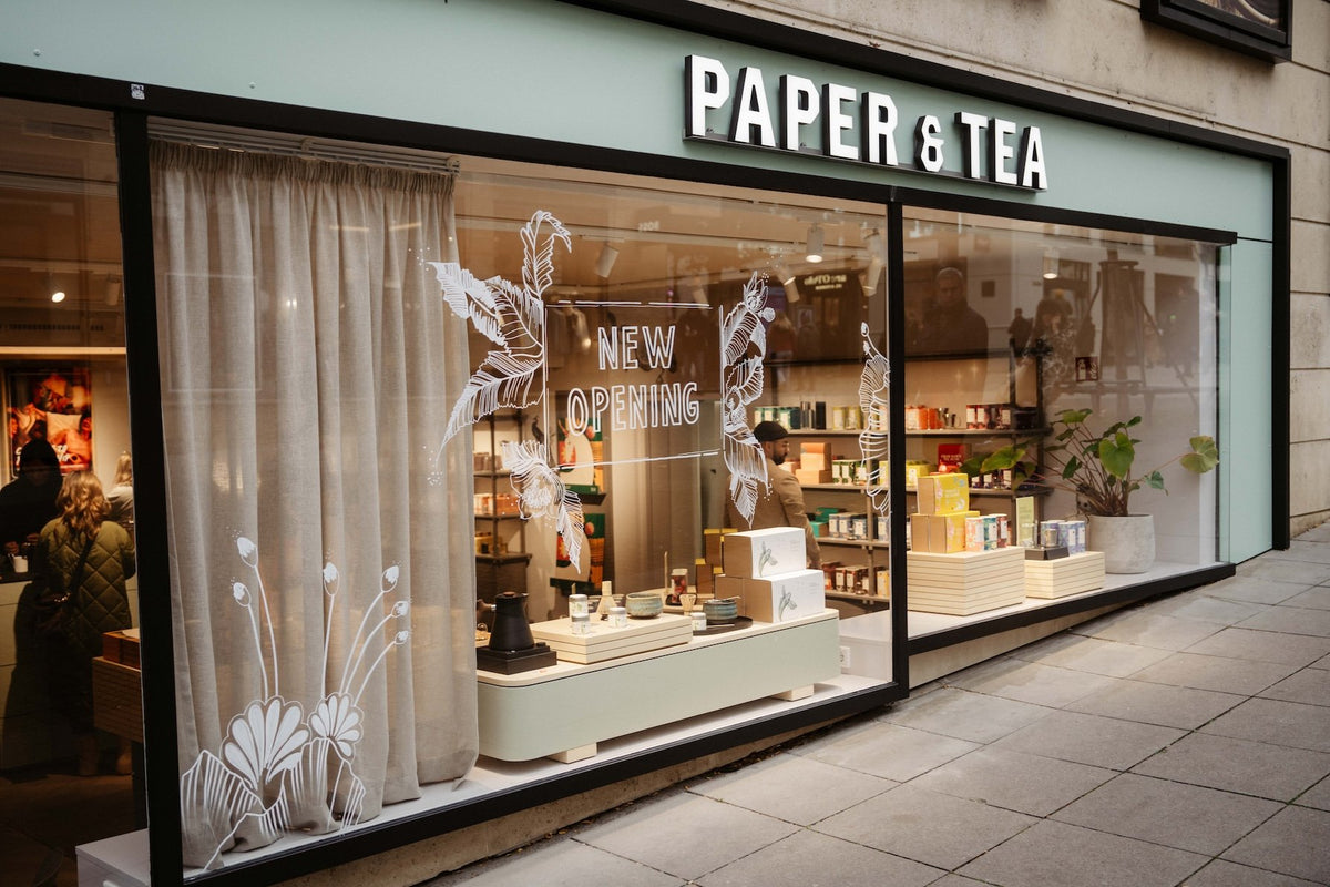 P&T Teegeschäft mit modernen Holzregalen, bunten Teeverpackungen und einladender Ladenfront.
